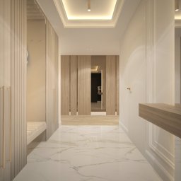 Ewelina Bulińska Architektura Wnętrz - Korytarz w jasnych barwach z marmurową podłogą i zabudową meblową z ryflowanymi frontami. W głębi drewniane drzwi i oświetlenie sufitowe.