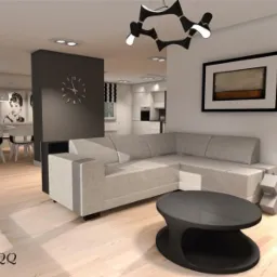 Wnętrze salonu z narożną sofą, okrągłym stolikiem kawowym i lampą podłogową. W tle jadalnia z czarno-białym zdjęciem Audrey Hepburn i kuchnia. Na ścianie zegar i obraz.