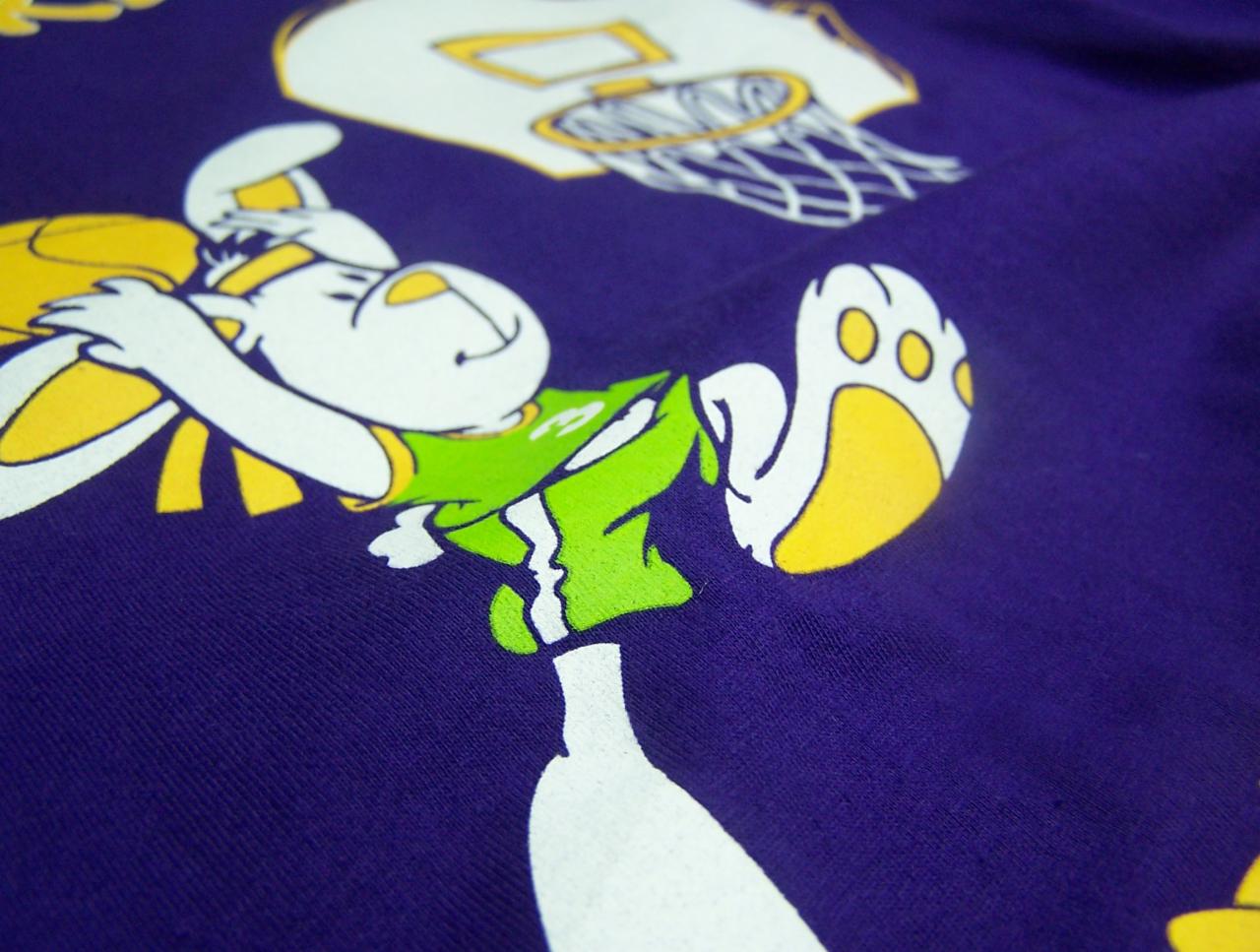 Fioletowa koszulka z nadrukiem kreskówkowego królika w sportowym stroju, wykonanym techniką sitodruku.