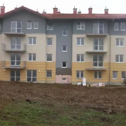 Wielki Klincz: Trzysegmentowy budynek po tynkowaniu elewacji, widoczne balkony i okna zabezpieczone folią, prace wykończeniowe w toku.