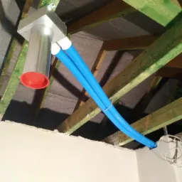 Instalacja rekuperacji z dwoma niebieskimi przewodami w domu w Sośnicowicach, widoczne elementy mocujące do drewnianej konstrukcji dachu.