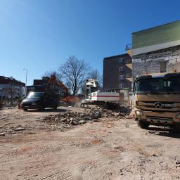 Przedsiębiorstwo Budowlano Transportowe Stefan Zakrzewski - Teren po rozbiórce budynku z widocznym gruzem, dwoma koparkami, ciężarówką Mercedes i czarnym busem w tle, słoneczny dzień.
