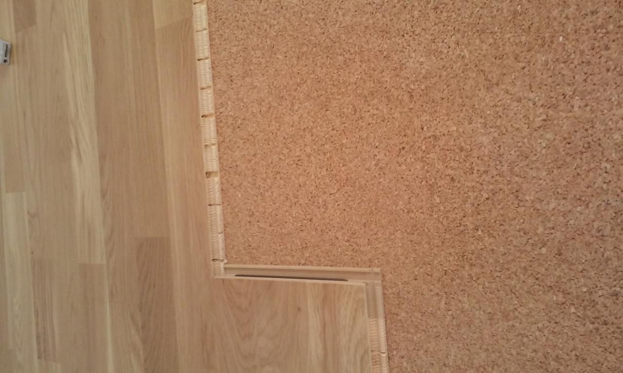 Układanie paneli podłogowych na podkładzie korkowym, widoczne połączenia paneli.