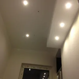 Sufit podwieszany z oświetleniem punktowym w Sępólnie Krajeńskim. Białe ściany i widoczny fragment okna. Nowoczesny design.