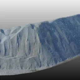 Sfotografowany pod kątem pryzmat bryły węgla z widocznymi śladami po przesuwaniu i transportowaniu.