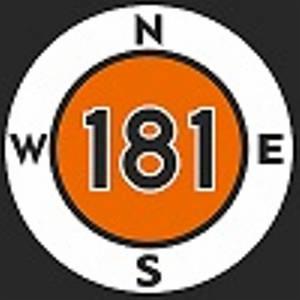 Okrągły, pomarańczowo-biały znak z liczbą 181 i literami kierunków świata (N, E, S, W). Znak umiejscowiony w Strzelnie.
