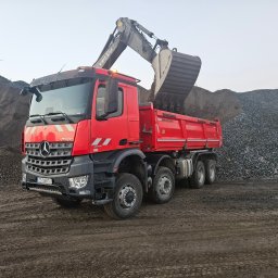 PHU RADOSŁAW BARANOWSKI - Czerwona ciężarówka Mercedes-Benz z otwartą skrzynią ładunkową, na którą koparka Volvo nabiera żwir z hałdy, widoczny numer rejestracyjny ZS 068TU, teren błotnisty.