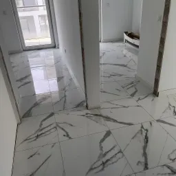 Błyszcząca, biała podłoga z marmurowym wzorem w jasnym wnętrzu. Widoczne niedokończone wykończenia ścian i podłogi. Nowoczesny design i jasne kolory.