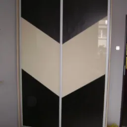 Dwudrzwiowa szafa przesuwna z frontami w kolorze czarnym i beżowym, tworzącymi wzór strzałki skierowanej w dół.