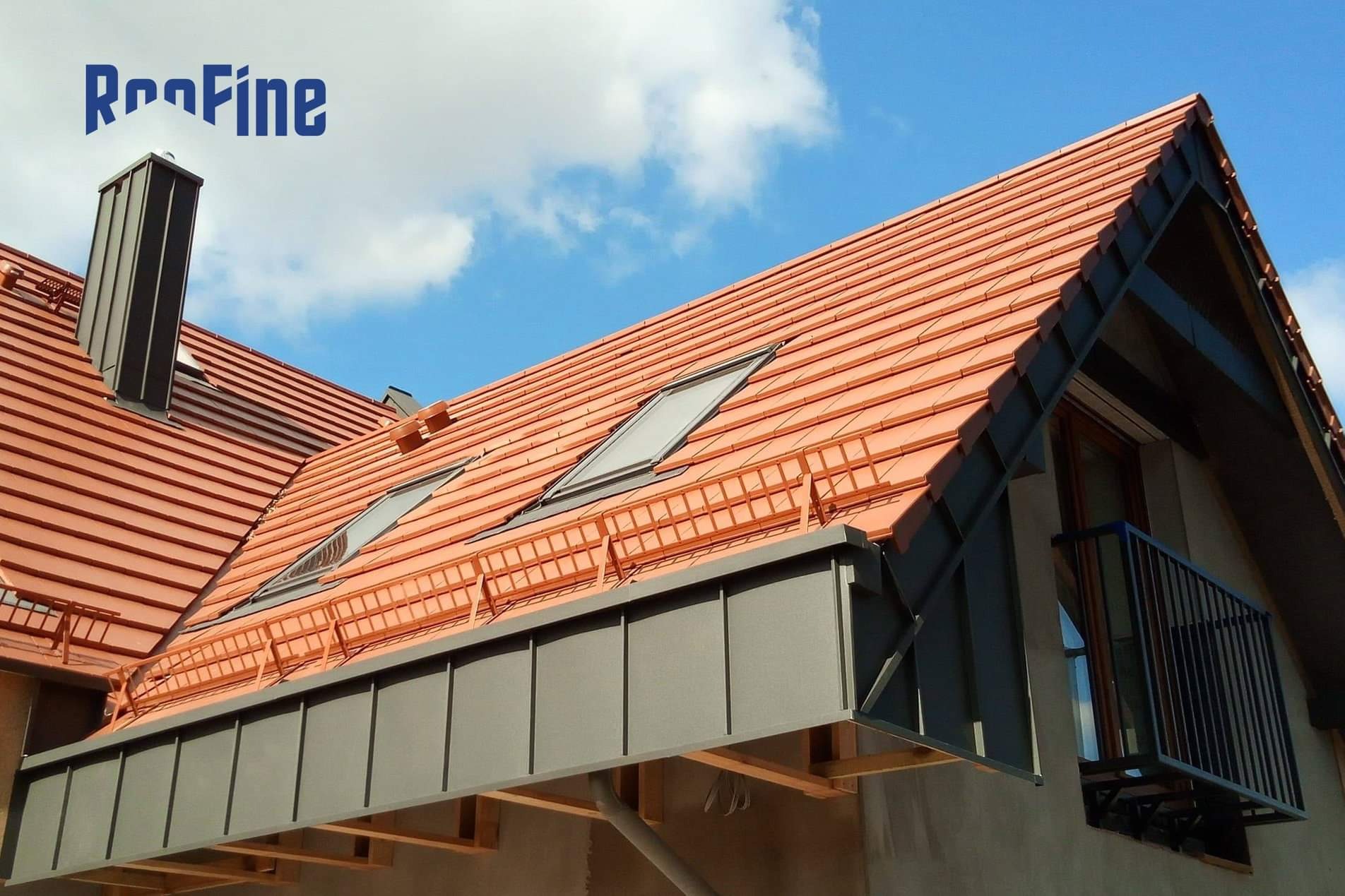 Nowy dach z czerwonej dachówki ceramicznej z oknami dachowymi i ciemnoszarą obróbką blacharską, widoczny komin i balkon.