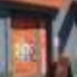 Mężczyzna w ciemnych spodniach i butach sportowych stoi przy bankomacie Euronet w pomarańczowej obudowie, wpisując kod na klawiaturze.