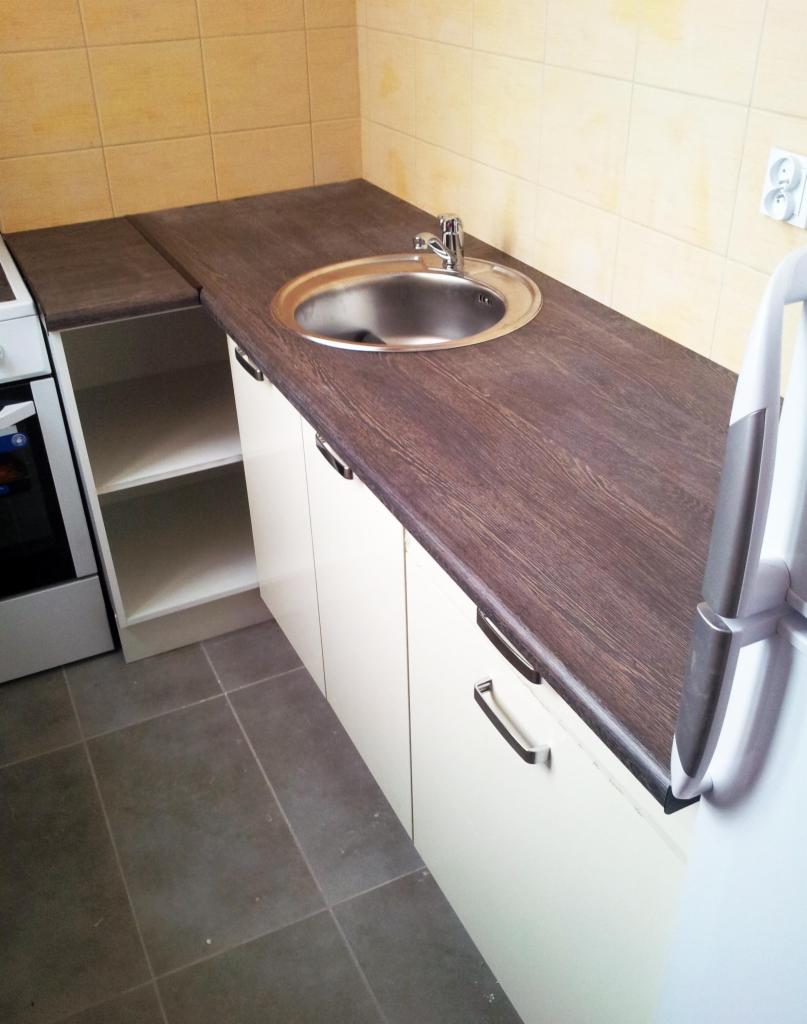 Nowoczesna, jasna zabudowa kuchenna ze zlewozmywakiem i blatem imitującym drewno, widok z góry w Plewiskach. Ukończony remont łazienki.