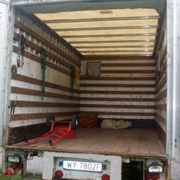 Ed-Mar Monika Kuraś - Wnętrze paki busa transportowego z wózkiem transportowym, zabezpieczeniami i tablicą rejestracyjną WY 7802F, widok z zewnątrz.