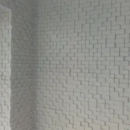 Ściana wewnętrzna wykończona trójwymiarowymi, białymi panelami o geometrycznym wzorze, widoczna z perspektywy narożnika pomieszczenia, obok okna.