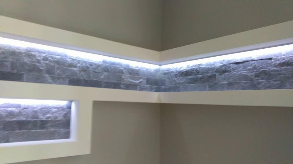 Dekoracyjna ściana z szarej cegły z podświetleniem LED w białej ramie. Nowoczesne wykończenie wnętrza, subtelne oświetlenie, minimalistyczny design.