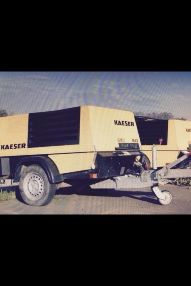 Dwie żółte przyczepy z kompresorami Kaeser na kołach, ustawione obok siebie na zewnątrz. Widoczne detale zaczepu i opon.