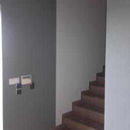 Art-bud Artur Wrzoszczyk - Klatka schodowa po malowaniu ścian na szaro, z widocznymi schodami wyłożonymi płytkami i zamontowanym systemem kontroli dostępu.