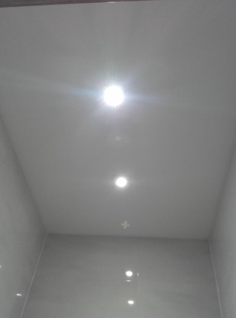 Biały sufit z trzema punktowymi lampami LED, widoczne odbicia światła na ścianach. Minimalistyczny design, świeżo po remoncie, brak dekoracji.