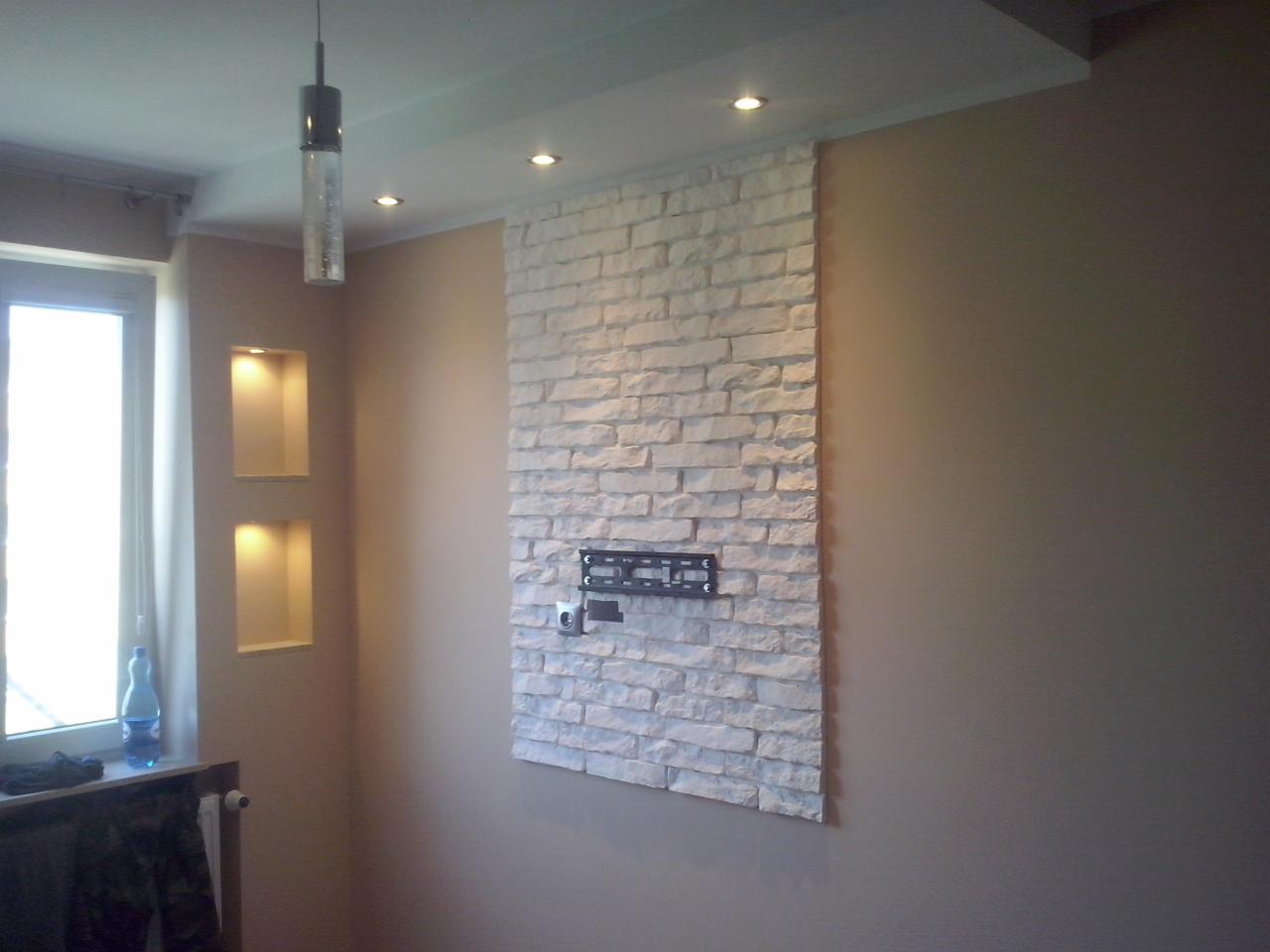 Ściana z dekoracyjnej białej cegły z uchwytem TV, podświetlane wnęki obok okna, Rumia. Nowoczesne wykończenie wnętrza, beżowe ściany, minimalistyczny design.