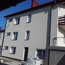 SPEC-THERM Grzegorz Piwowarski - Wielopiętrowy budynek mieszkalny po tynkowaniu elewacji w Miedzianej Górze, widoczne rusztowania i worki z odpadami po pracach wykończeniowych.