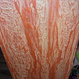 Loukas - Dekoracyjna ściana w odcieniach pomarańczy i złota z unikalną teksturą imitującą korę drzewa. Widoczne nieregularne wzory i subtelne refleksy świetlne.