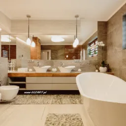 Nowoczesna łazienka z wolnostojącą wanną, dwoma umywalkami nablatowymi, bidetem i toaletą w odcieniach szarości z akcentami drewna i roślinami w oknie.