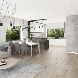 Jasne wnętrze salonu z jadalnią i kuchnią w stylu minimalistycznym. Widoczna sofa z niebieskimi poduszkami, okrągły stolik kawowy, dywan w odcieniach błękitu i beżu oraz stół z szarymi krzesłami.