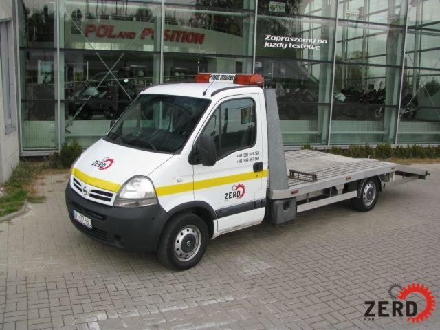 Biała laweta z żółtymi pasami i logo firmy ZERD na tle salonu samochodowego z napisem 'Zapraszamy na jazdy testowe'.