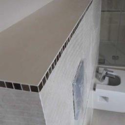 Remonty i wykończenia wnętrz TEAM CONCEPT - Wykończona łazienka z blatem wyłożonym mozaiką, umywalką i lustrem zabezpieczonym folią. Nowoczesny design w jasnych barwach.