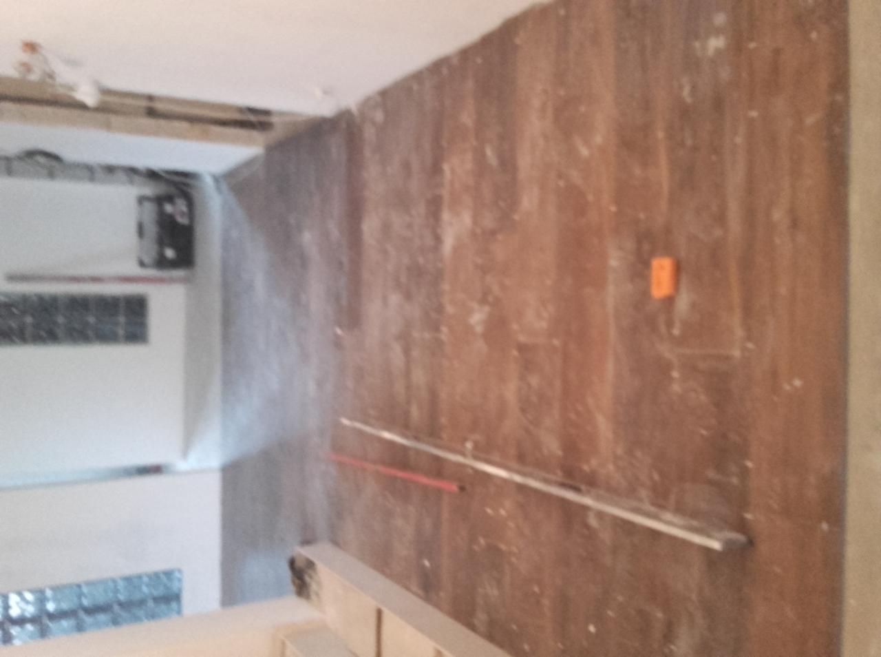 Ściana z widocznymi śladami gładzi, przygotowana do malowania, z zamontowaną listwą przypodłogową. Widoczny fragment instalacji elektrycznej.