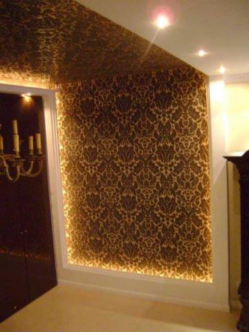 Eleganckie wykończenie wnętrza: ściana i sufit pokryte wzorzystą tapetą w odcieniach brązu i złota, subtelne oświetlenie punktowe, dekoracyjny charakter.