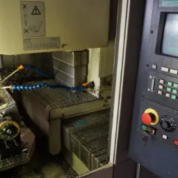 Wnętrze maszyny CNC Siemens w trakcie pracy, widoczne chłodziwo, obrabiany element oraz panel sterowania z wyświetlaczem.