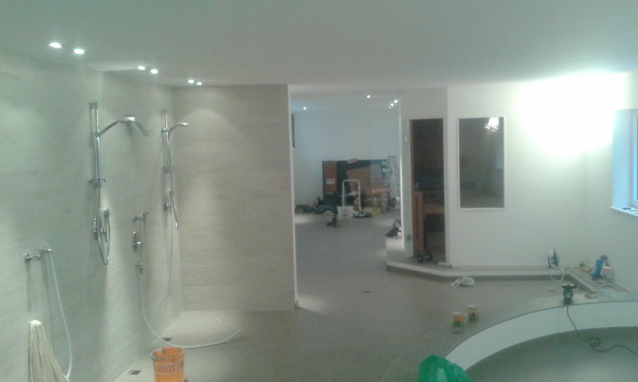 Jasna łazienka po remoncie z kabiną prysznicową typu walk-in i wanną. Widoczne narzędzia i materiały wykończeniowe.