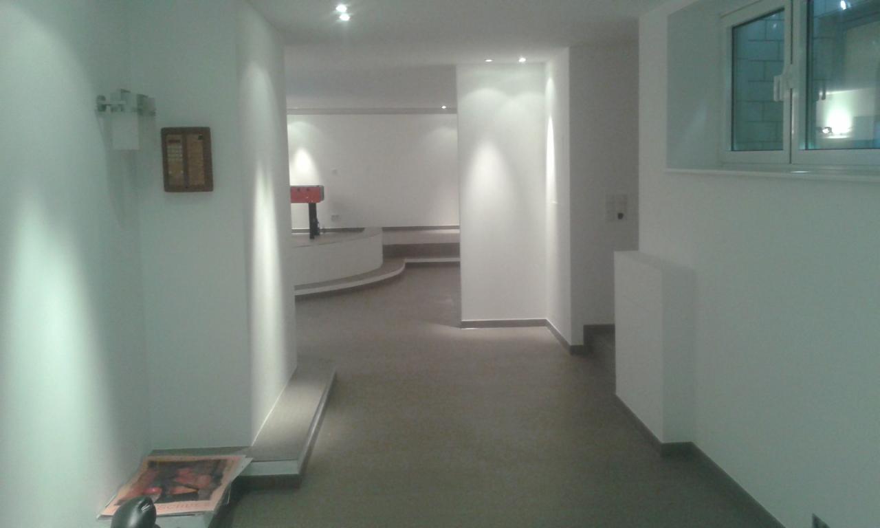 Jasne, przestronne wnętrze po remoncie z widocznym stołem do piłkarzyków w tle i świeżo pomalowanymi ścianami, oświetlone punktowymi lampami.