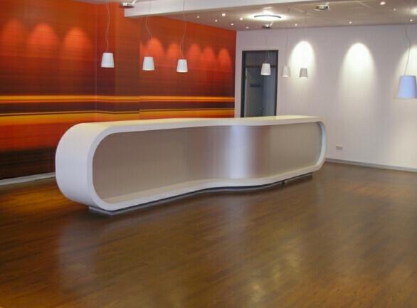 Nowoczesne, puste biuro z białą, futurystyczną recepcją na parkiecie, pomarańczowa ściana w tle i wiszące lampy.