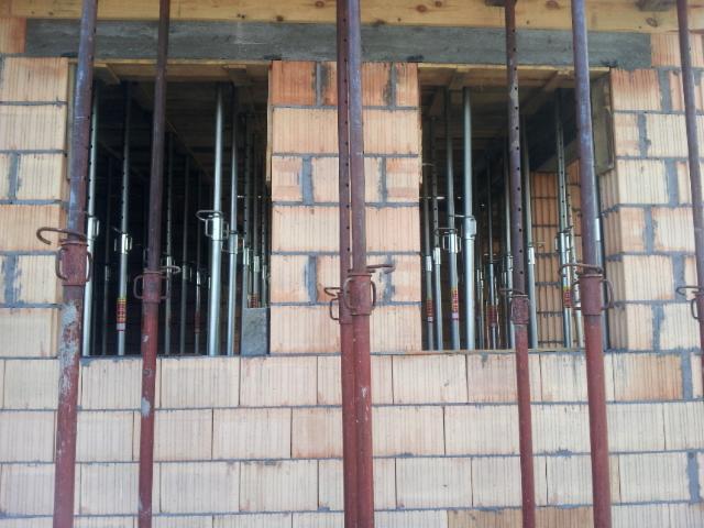 Murowanie ściany z pustaków ceramicznych z podporami w Krosno Odrzańskie. Widoczne szalunki i stemple budowlane podtrzymujące strop.