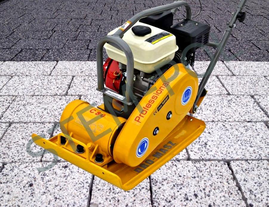Żółta zagęszczarka spalinowa DROMASZ C80 na kostce brukowej. Widoczny silnik, uchwyt i płyta wibracyjna. Sprzęt budowlany do ubijania gruntu.
