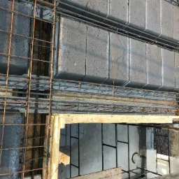 Wiązanie zbrojenia na szalunku fundamentów z bloczków betonowych, widok z góry na budowę.