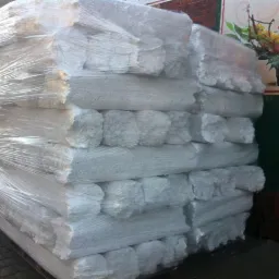 Stos belek wapiennych zabezpieczonych folią stretch na palecie, gotowych do transportu. Widoczne nierówne krawędzie i struktura materiału.