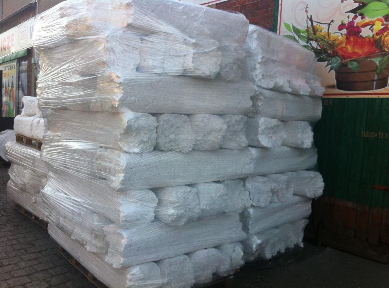 Stos belek wapiennych zabezpieczonych folią stretch na palecie, gotowych do transportu. Widoczne nierówne krawędzie i struktura materiału.