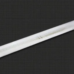 Podłużna lampa LED w białej obudowie na ciemnym, teksturowanym tle. Widoczne drobne diody LED wewnątrz klosza. Minimalistyczny design, idealny do nowoczesnych wnętrz.