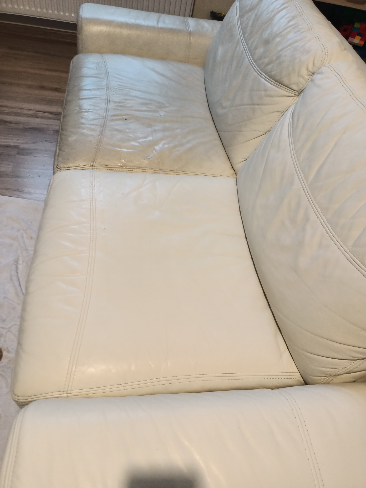Fragment białej, skórzanej kanapy z widoczną różnicą w czystości pomiędzy wyczyszczoną a nie wyczyszczoną częścią siedziska.