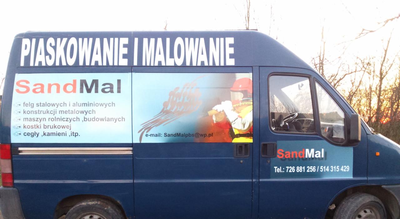 Reklama usług piaskowania i malowania na niebieskim busie firmy SandMal. Widoczny kontakt telefoniczny i adres e-mail. Na grafice osoba w kasku ochronnym.