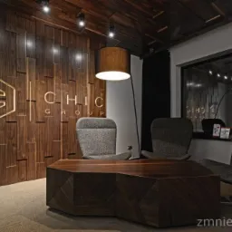 Recepcja z panelami ściennymi 3D z logo firmy 'Chic Group' w Namysłowie, oświetlona lampą podłogową, z widocznymi trzema fotelami i stolikiem kawowym.