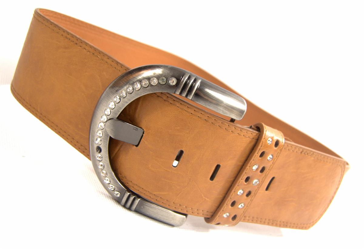 Szeroki, brązowy skórzany pasek damski z dużą, zdobioną kryształkami, metalową klamrą w kształcie podkowy, leżący na białym tle.