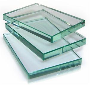 Stos tafli szkła o gładkich krawędziach, ułożonych warstwowo, z delikatnym zielonkawym odcieniem, na jasnym tle. Widoczne refleksy świetlne.