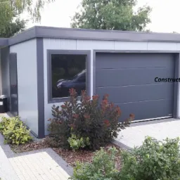 Nowoczesny garaż blaszany z bramą segmentową w Sulejówku, z dodatkowym pomieszczeniem gospodarczym i starannie zagospodarowanym otoczeniem.