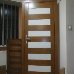 Zamknięte, brązowe drzwi wewnętrzne z poziomymi, białymi panelami. Obok stoi drewniana szafka z żaluzjowymi drzwiczkami. Widoczny fragment okna z żaluzjami.