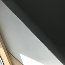 Usługi budowlane Makowski - Wnętrze okna dachowego po umyciu, widoczna czysta, biała powierzchnia ramy i szyby, kontrastująca z ciemnym sufitem.