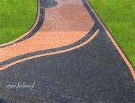 Ogród z mozaiką z kostki brukowej: czarna obwódka, pomarańczowy wzór i zielony trawnik. Widok z góry na ścieżkę wijącą się między trawnikami.